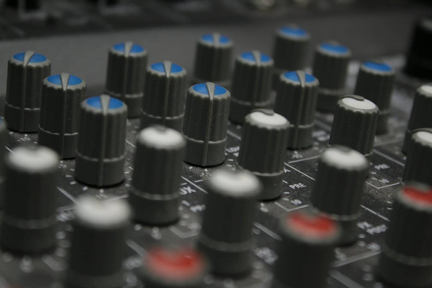 Audio-Mischpult mit vielen grauen Reglern und farbigen Anzeigen.